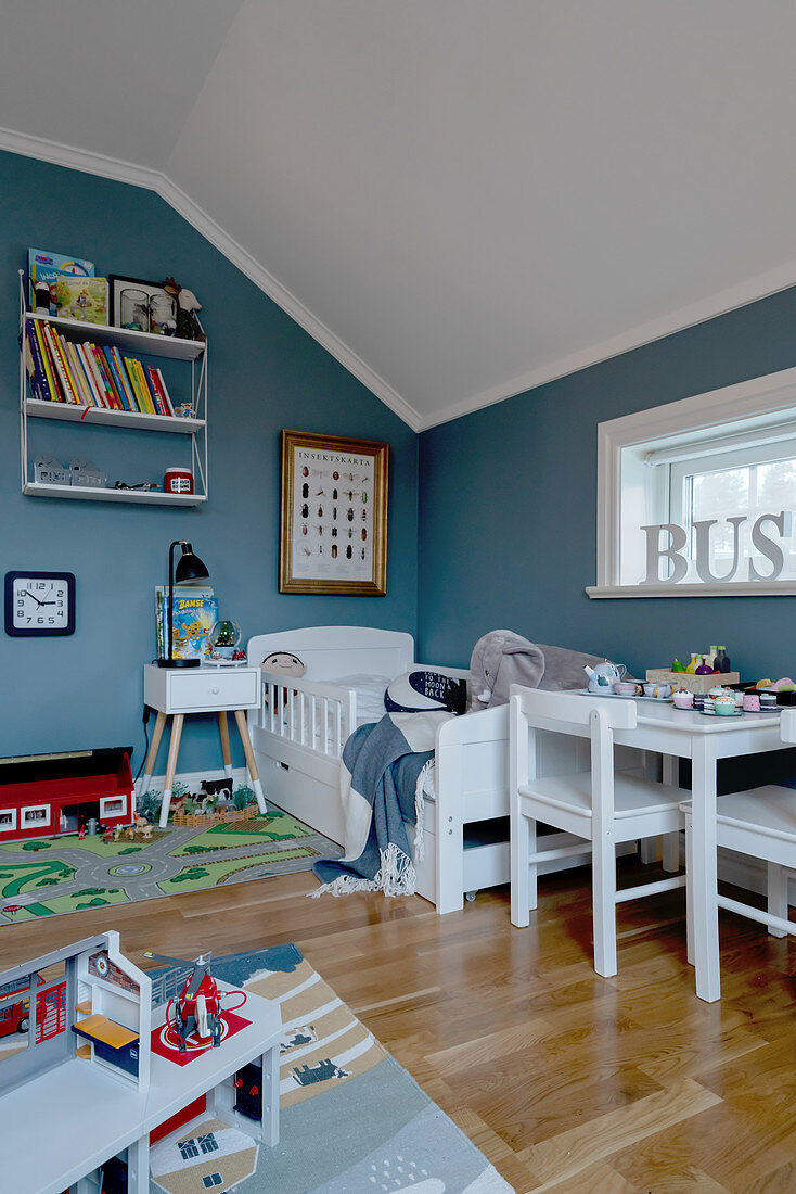 Kinderzimmer unter der Schräge mit blauer Wand und weißen Möbeln