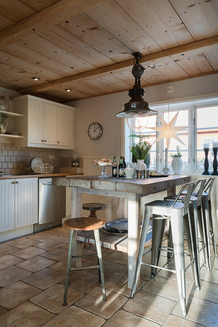 Rustic wooden table and metal stools in country-house kitchen
