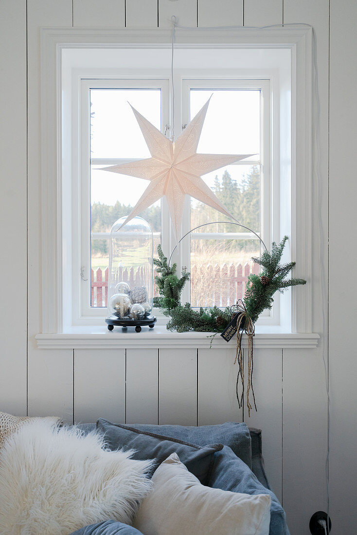 Papierstern und minimalistischer Weihnachtskranz am Fenster