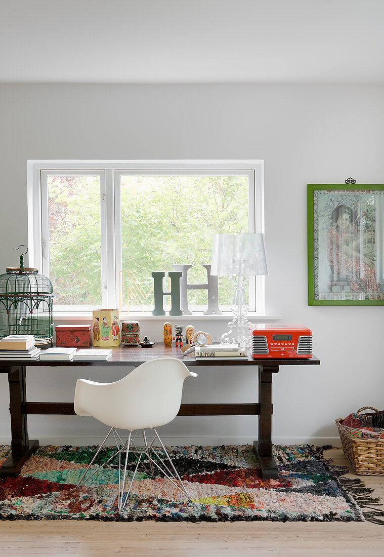 Designerstuhl am alten Holztisch mit Vintagedeko vorm Fenster
