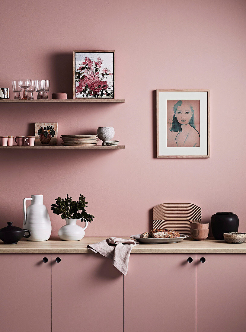 Shelves above the sideboard in a homely kitchen all in antique pink