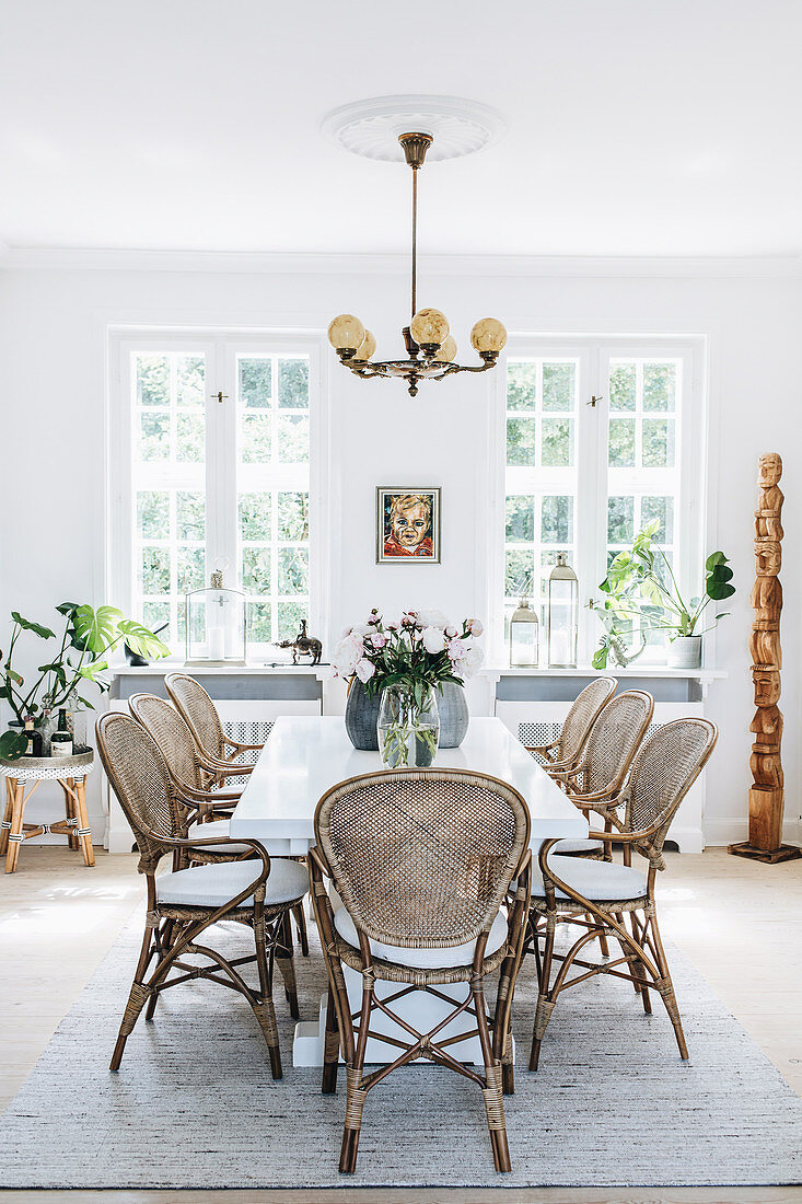 White dining table with rattan chairs in light dining room