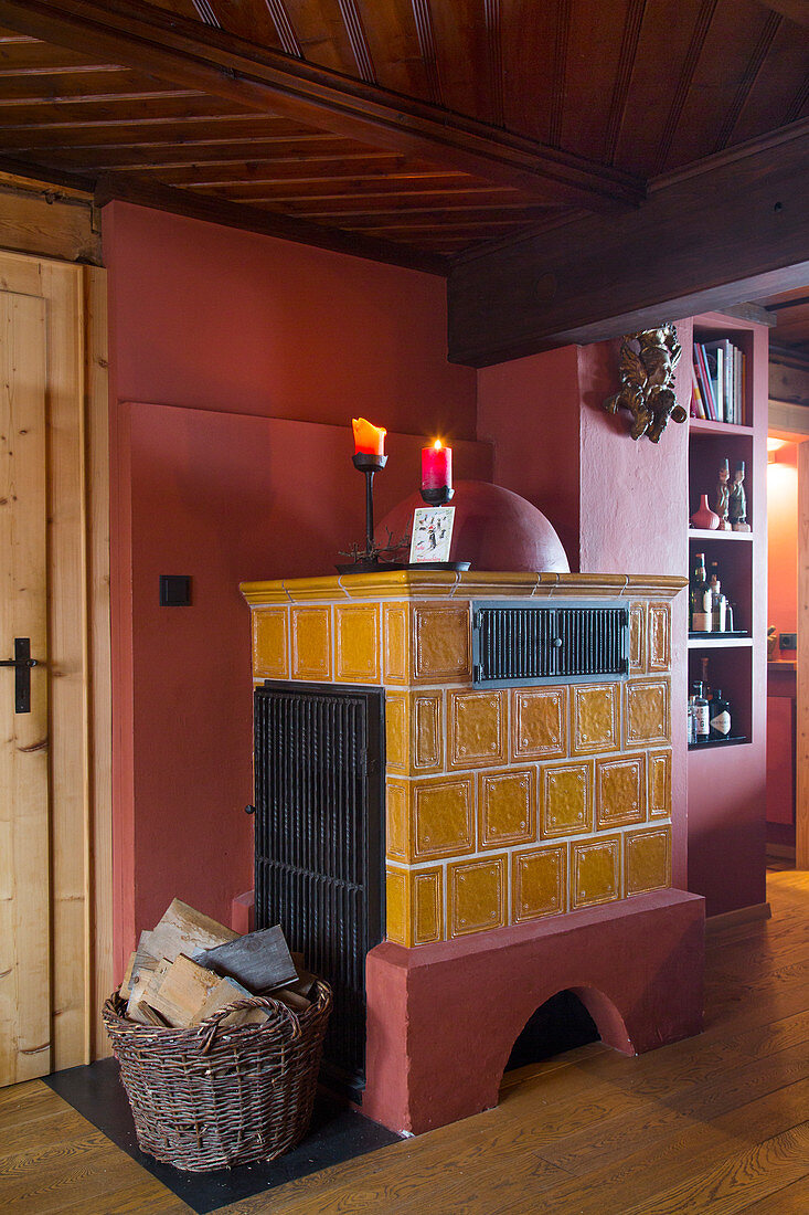 Yellow tiled stove against red wall in rustic living room