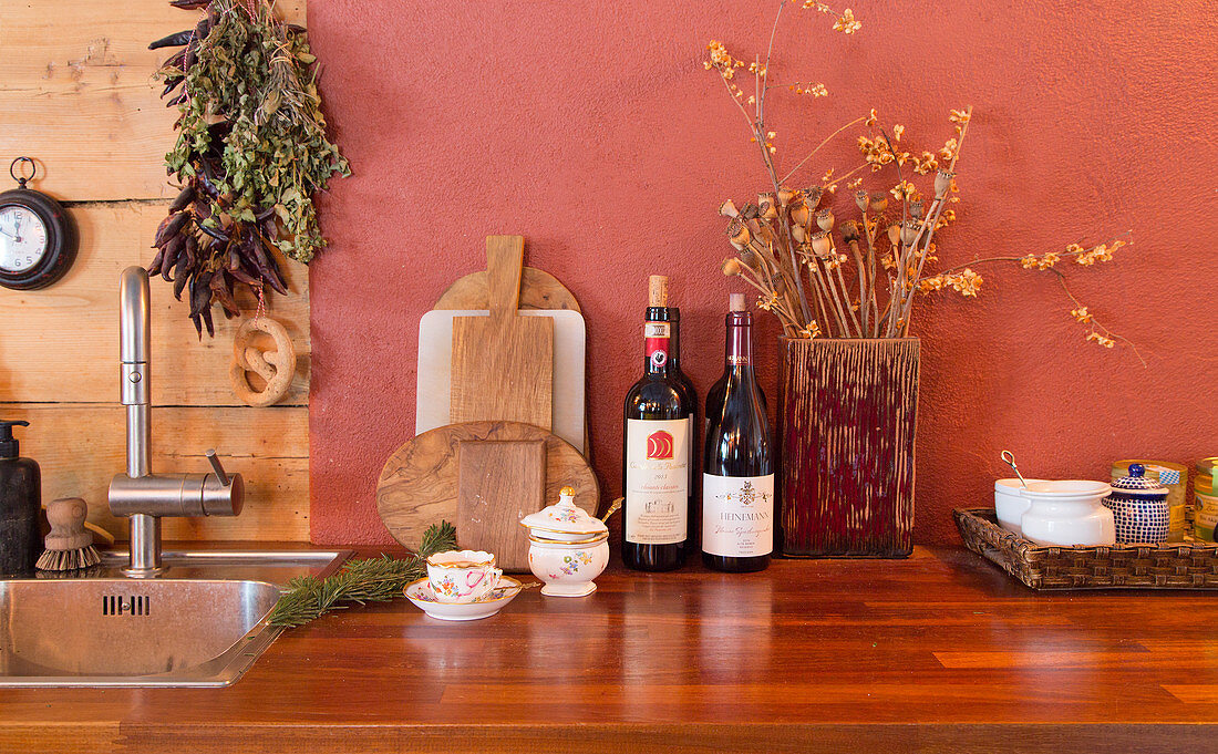 Schneidebrettchen, Wein und Trockenblumen in Holzvase