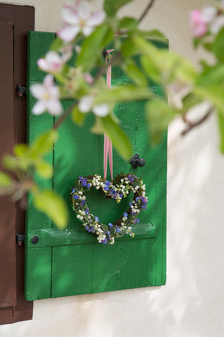 Heart-shaped wreath of lily-of-the-valley and forget-me-nots on window shutter