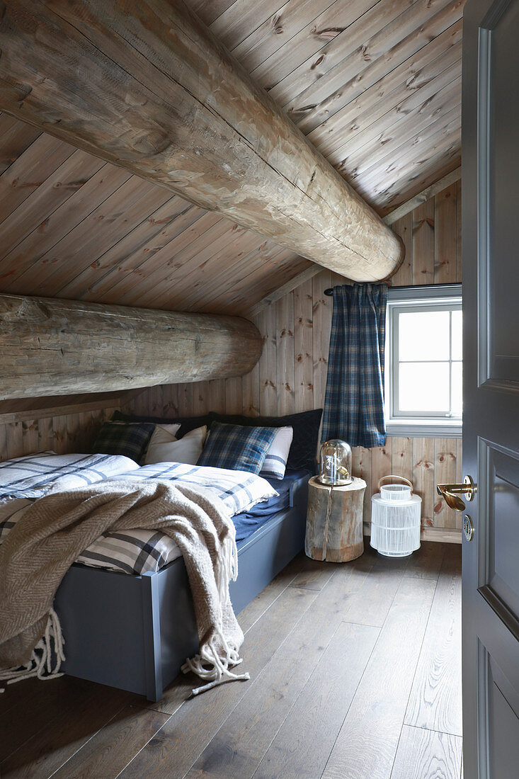 Rustic bedroom under sloping ceiling of log cabin