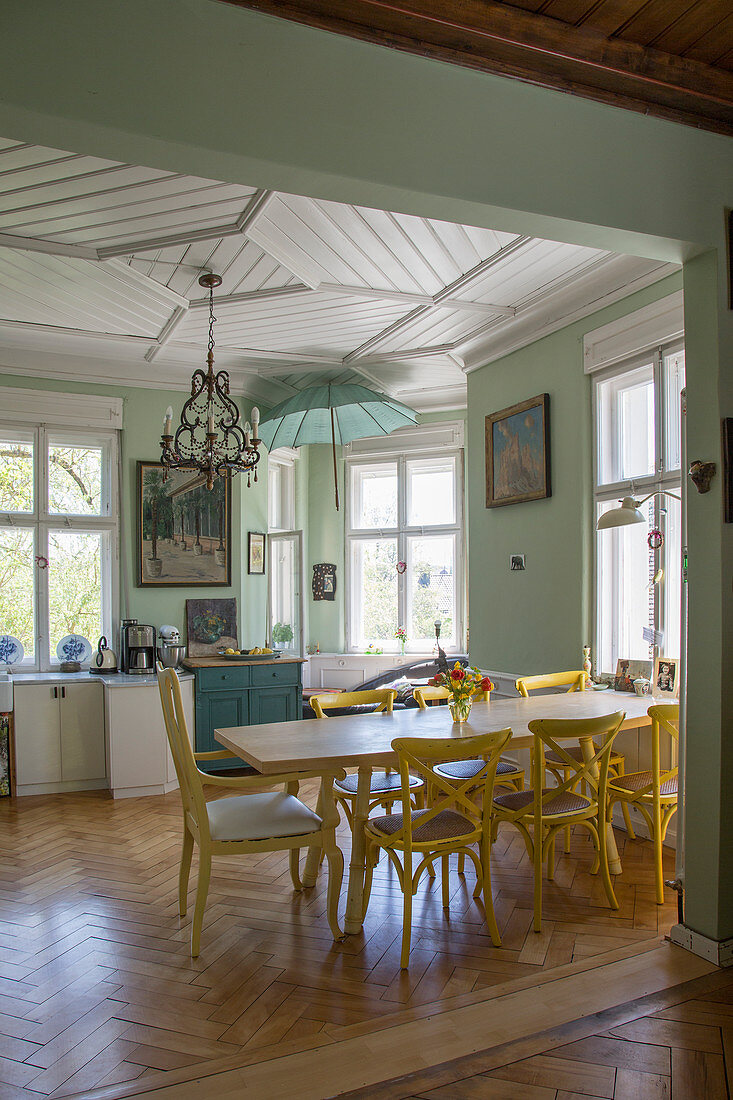 Yellow chairs around dining table in open-plan kitchen with panelled ceiling