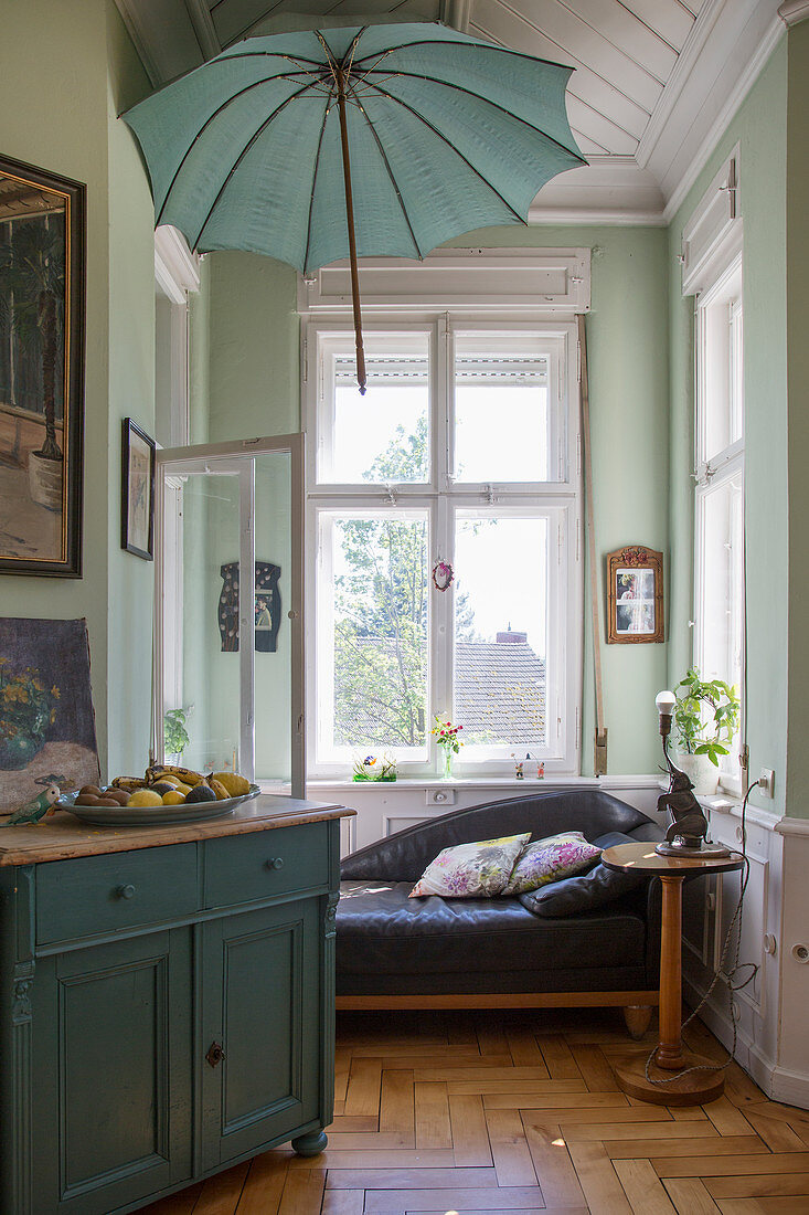 Parasol above sofa in window bay with mint-green walls in period building