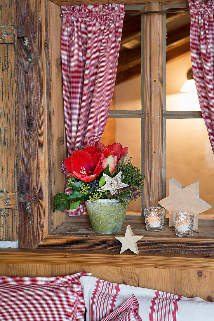 Gesteck mit Amaryllis und Holzsterne am Fenster in Bauernstube