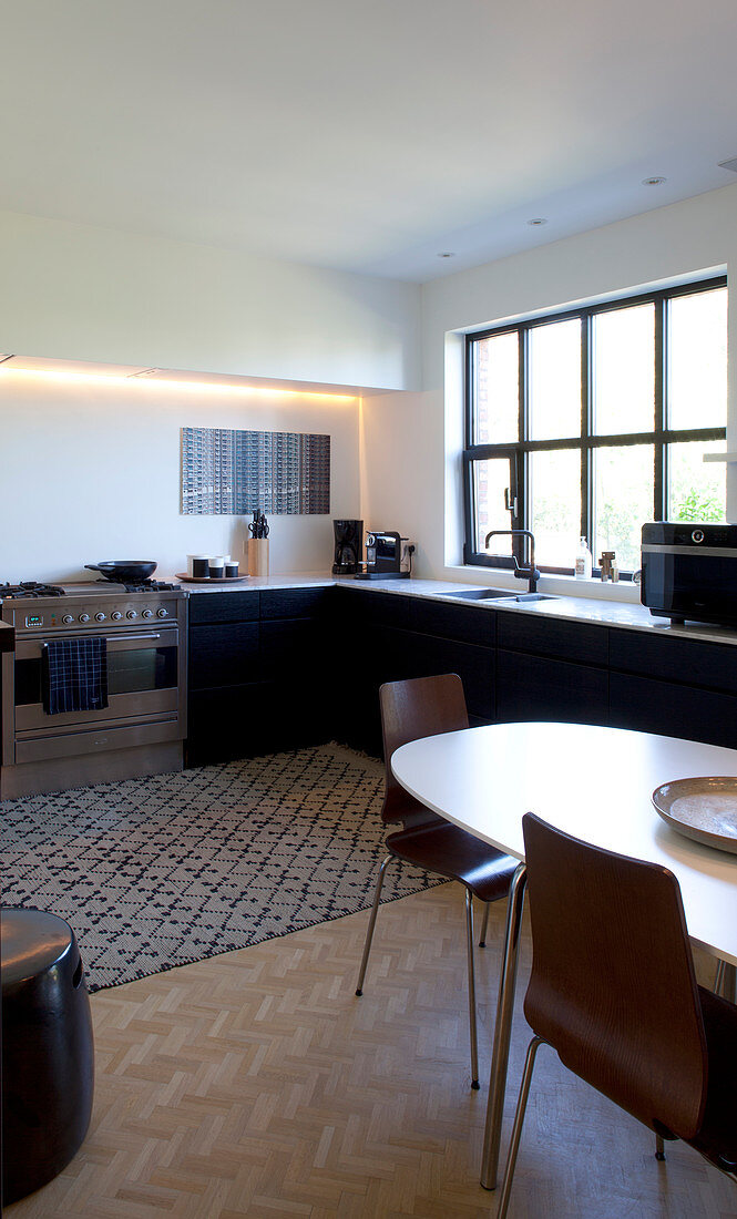 Ovaler Esstisch in großer Wohnküche mit schwarzen Fronten