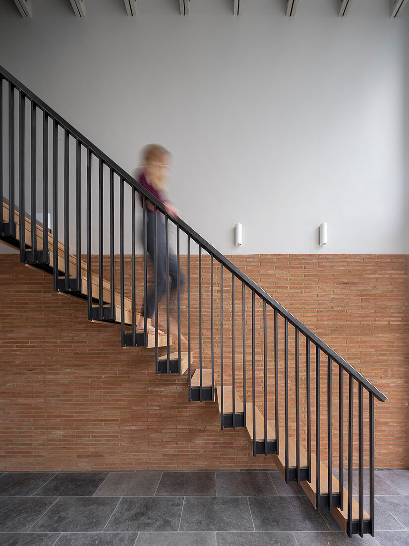 Frau in Bewegungsunschärfe geht freitragende Treppe hinunter