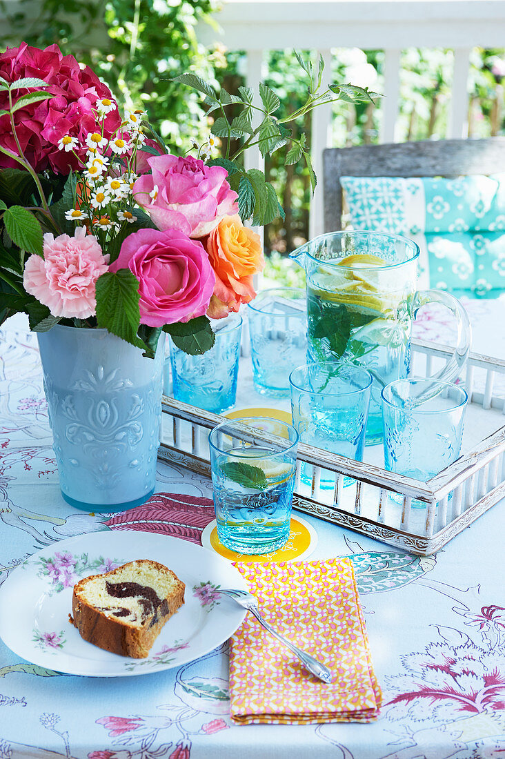 Sommerlicher Blumenstrauß, Limonade und Kuchen auf Tisch