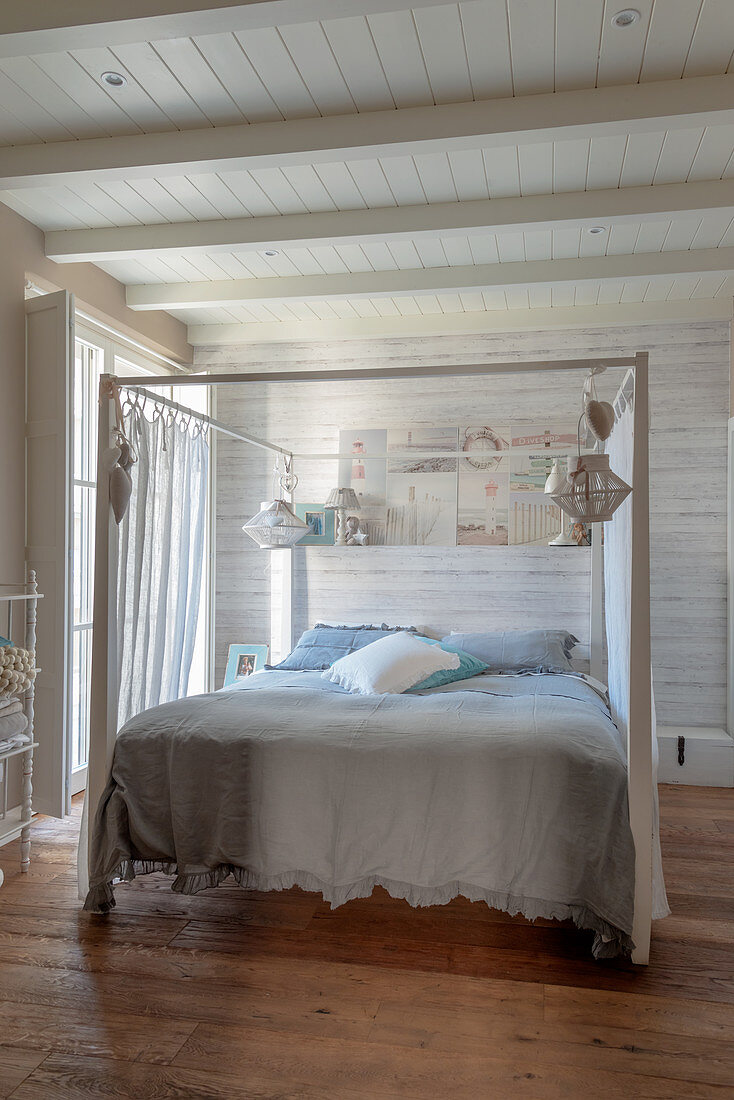 Doppelbett mit Baldachin im Schlafzimmer mit weiß gestrichener Holzwand