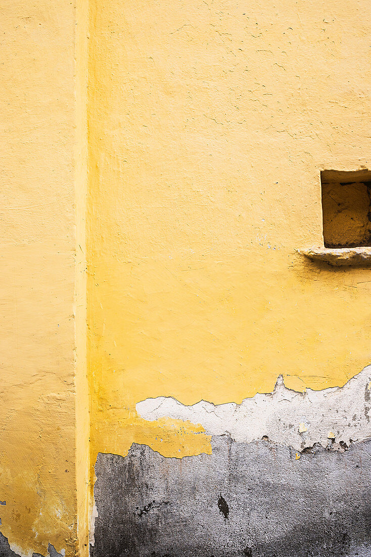 Gelbe Hauswand mit Nischenöffnung und abgeblätterter Farbe