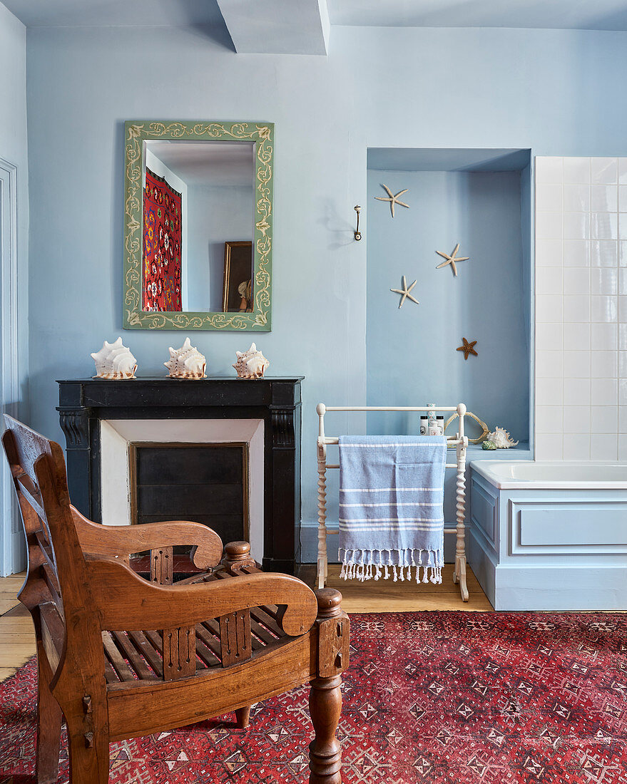 Carved wooden chair in light blue bathroom with seashells