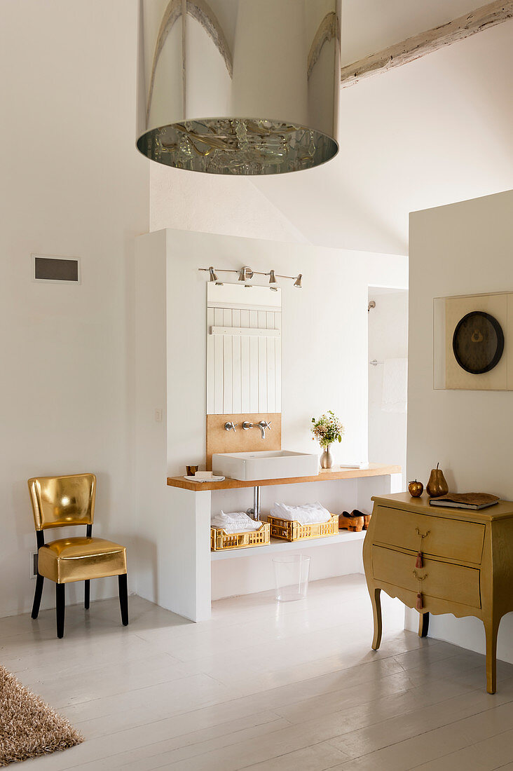 Glamouröser goldener Stuhl im weißen offenen Badezimmer mit französische Kommode