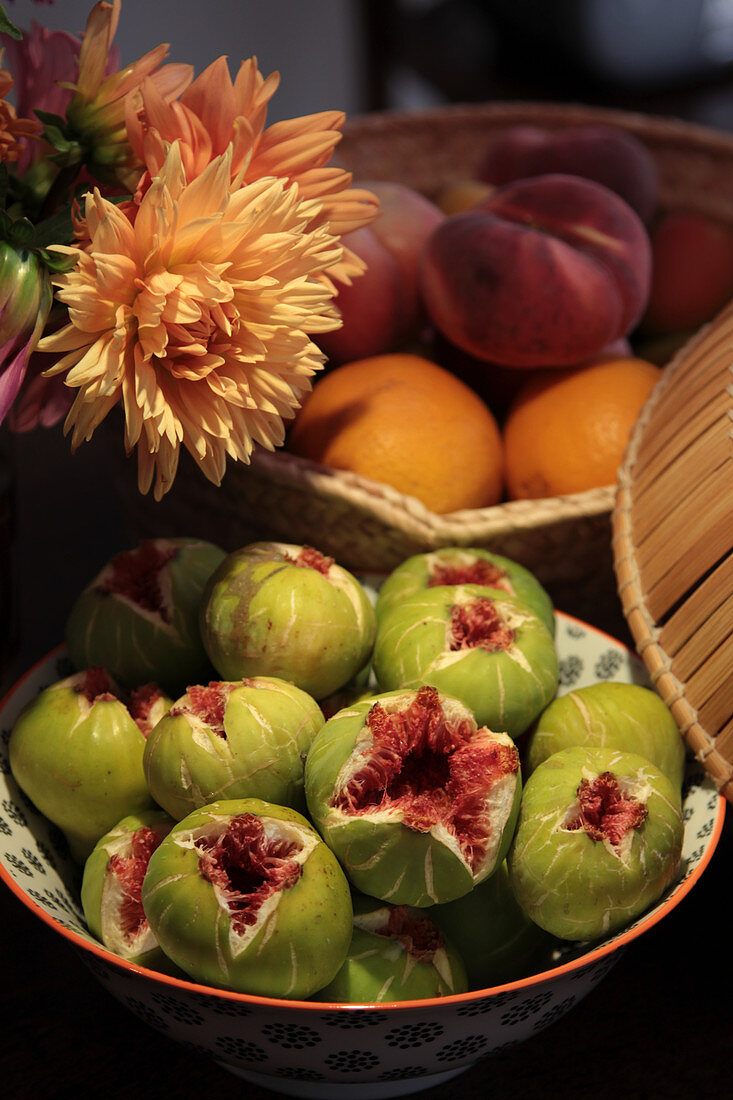 Still life with ripe figs, dahlias and bowl with oranges and peaches