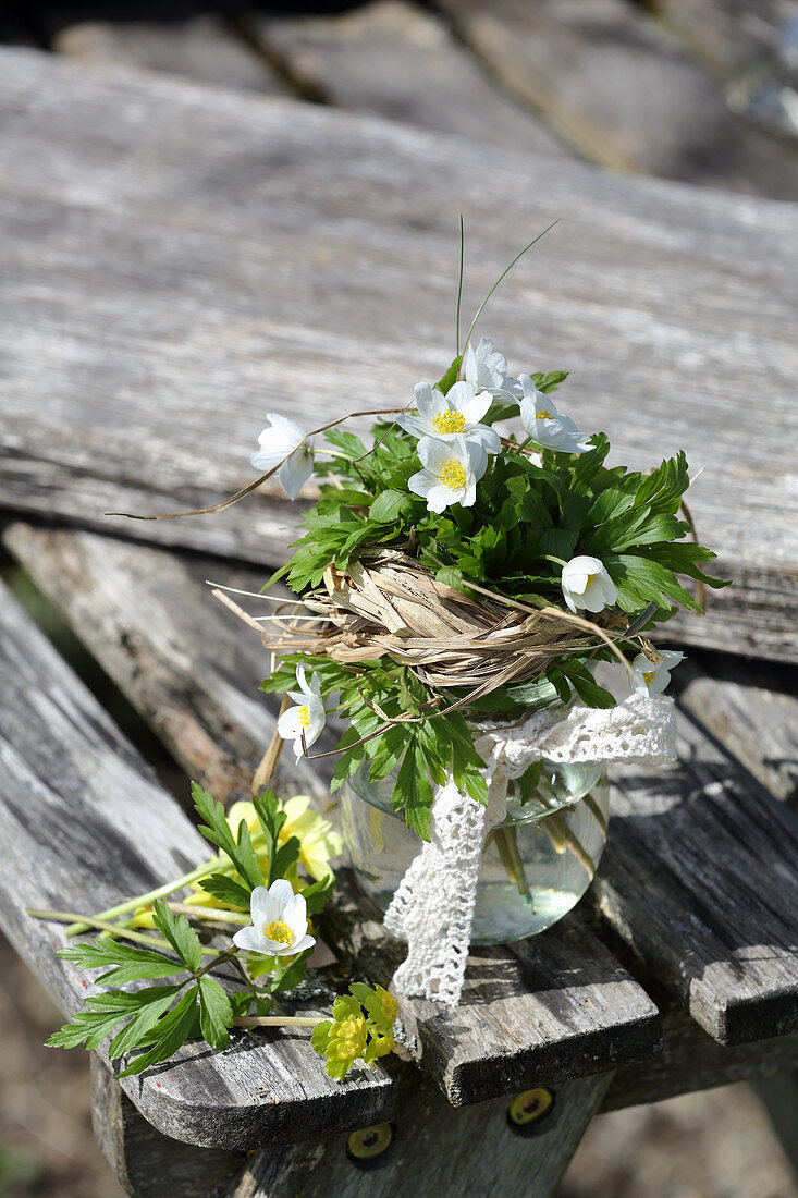 A small bouquet of wood anemones with a grass cuff and lace ribbon