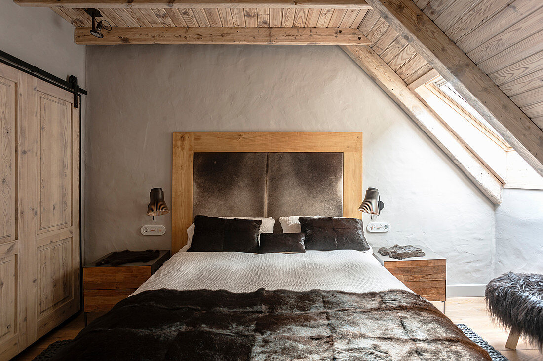 Luxuriöses Doppelbett im Schlafzimmer mit Holzdecke und Fenster