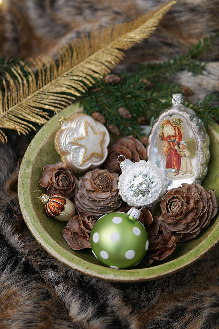 Vintage-style Christmas tree decorations and pine cones in bowl