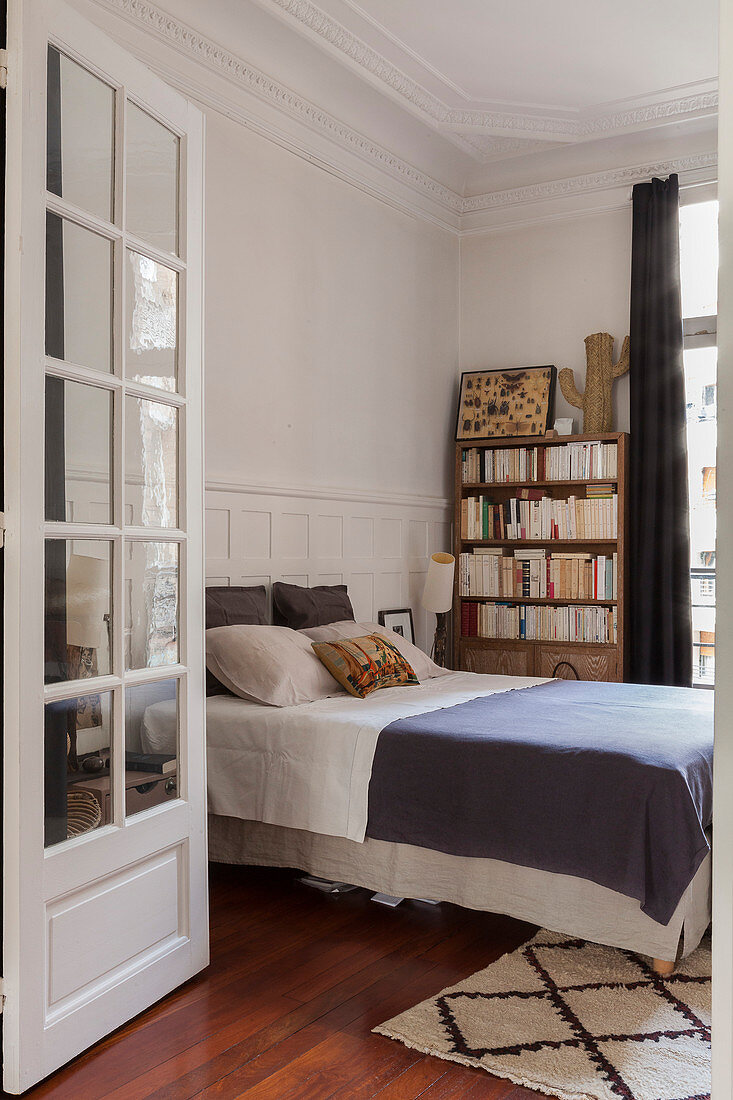 Blick ins Schlafzimmer mit Doppelbett und Bücherregal