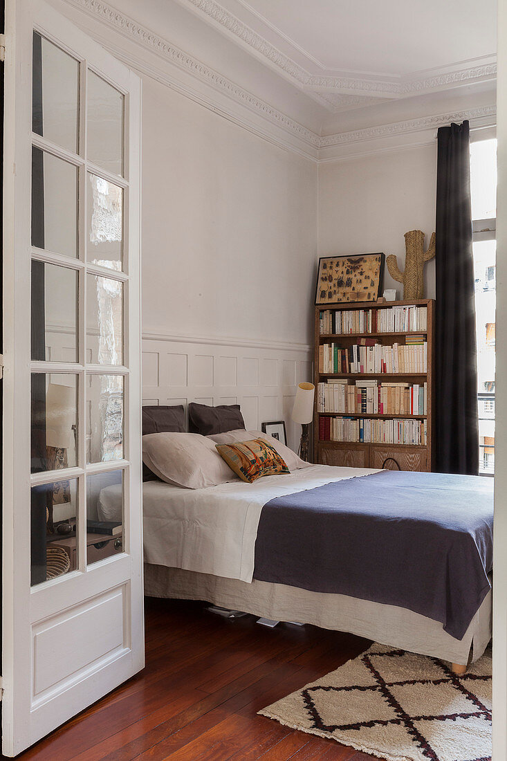 View into bedroom with double bed and bookcase