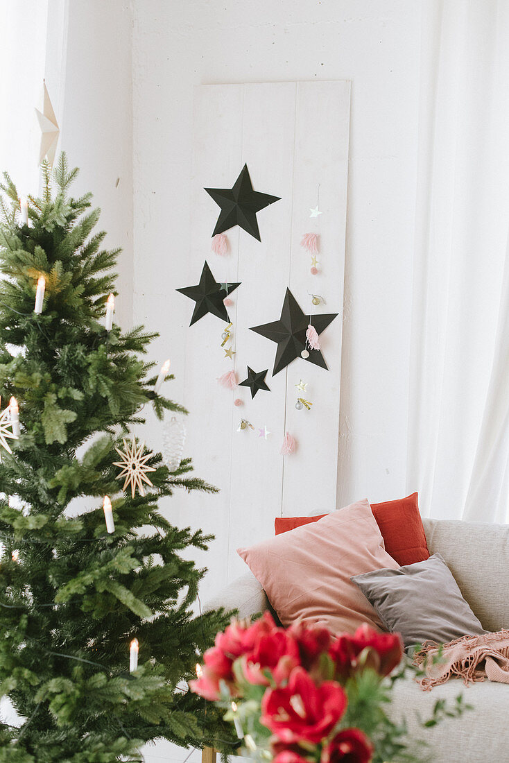 Decorated Christmas tree and paper stars on white wooden panel