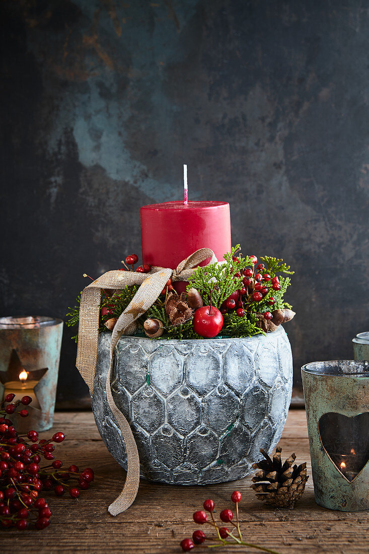 Weihnachtliches Gesteck mit roter Kerze im grauen Blumentopf