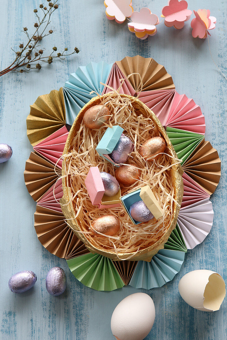 Chocolate eggs in Easter next surrounded by frame of paper fans