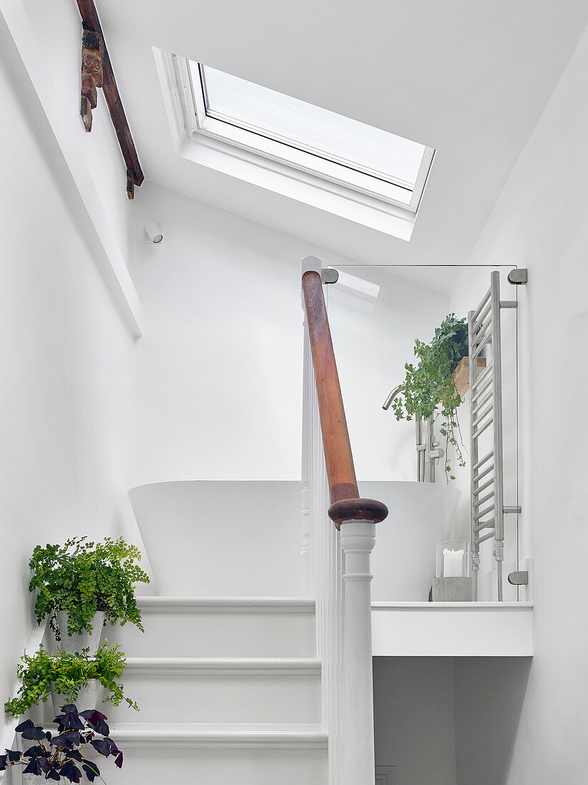 Treppenaufgang zum Splitlevel unter Dachschräge mit freistehender weißer Badewanne
