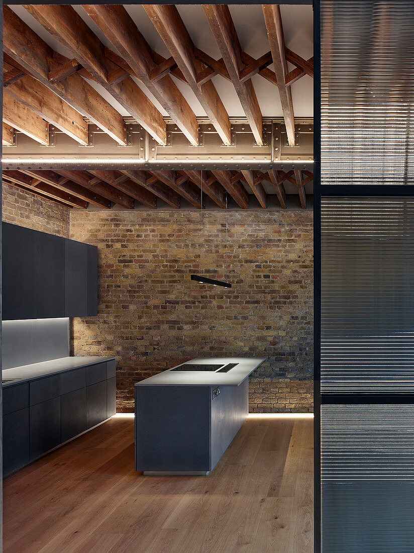 Modern monochrome kitchen with wood-beamed ceiling in restored brick house