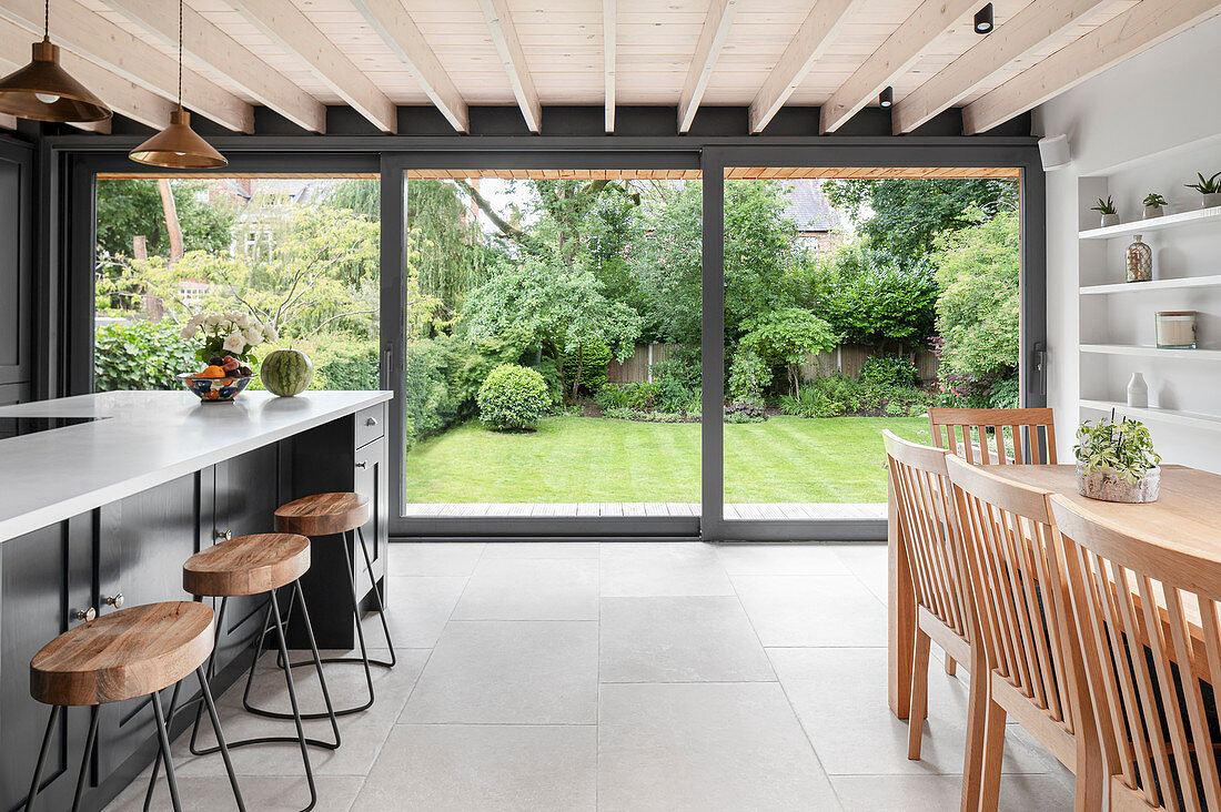 Modern kitchen-dining room with glass wall overlooking garden