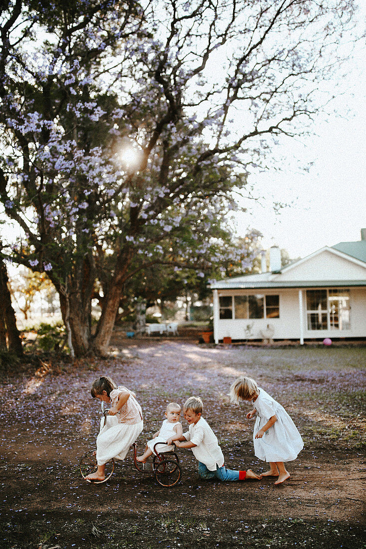 Children in white clothes playing in front of a house in the countryside
