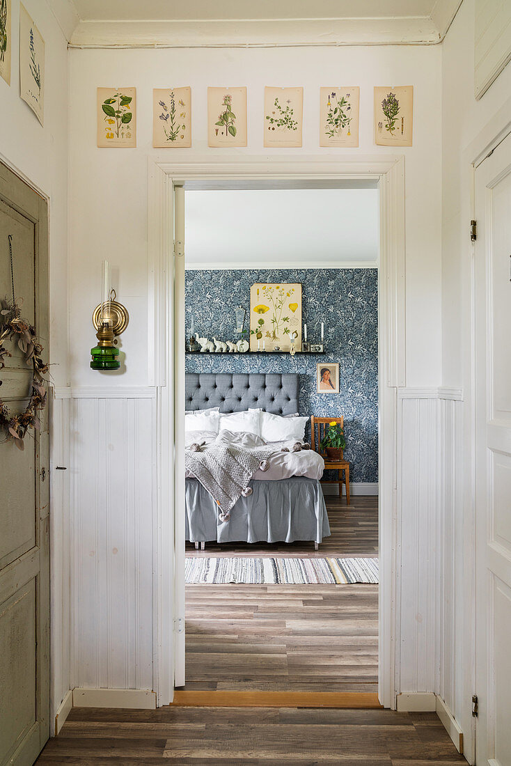 Blick durch geöffnete Tür ins Schlafzimmer mit Doppelbett und blau gemusterter Tapete