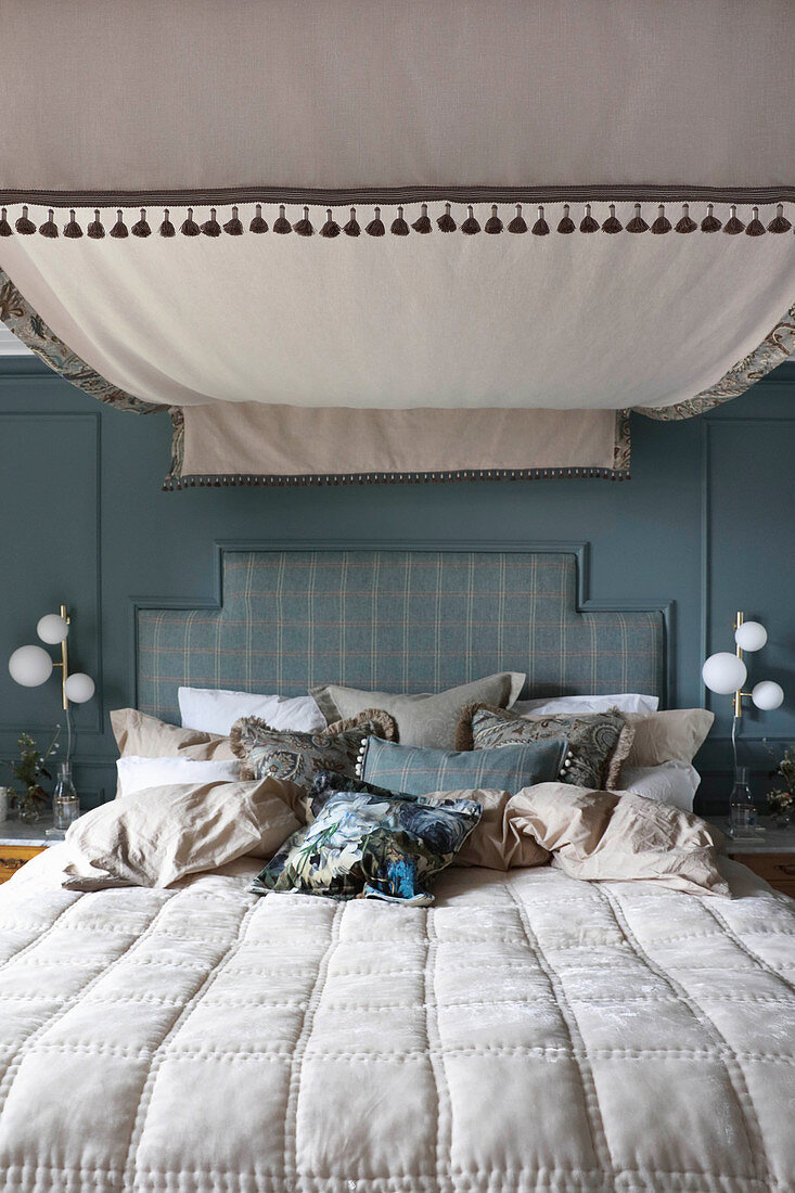 Double bed with canopy against blue wall in rustic bedroom