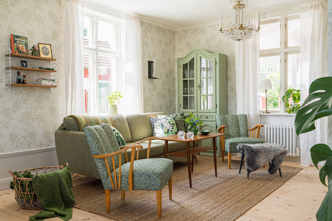 Green upholstered furniture, dresser and patterned wallpaper in living room