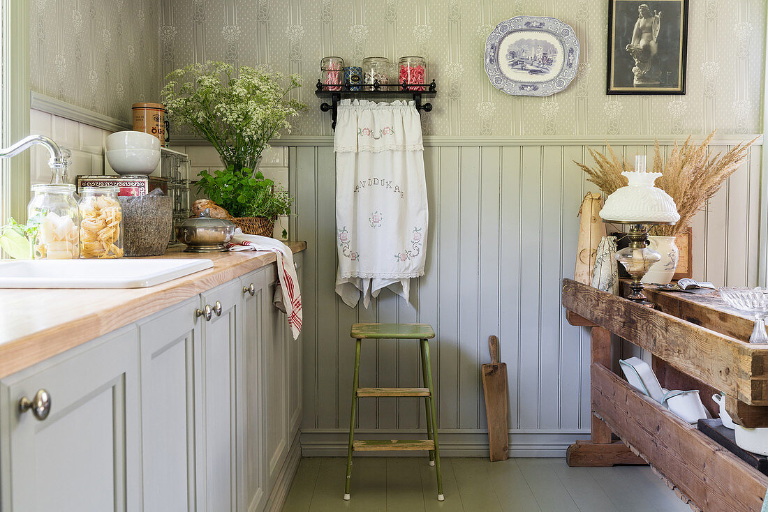Grey cabinets and antique table in country-house kitchen