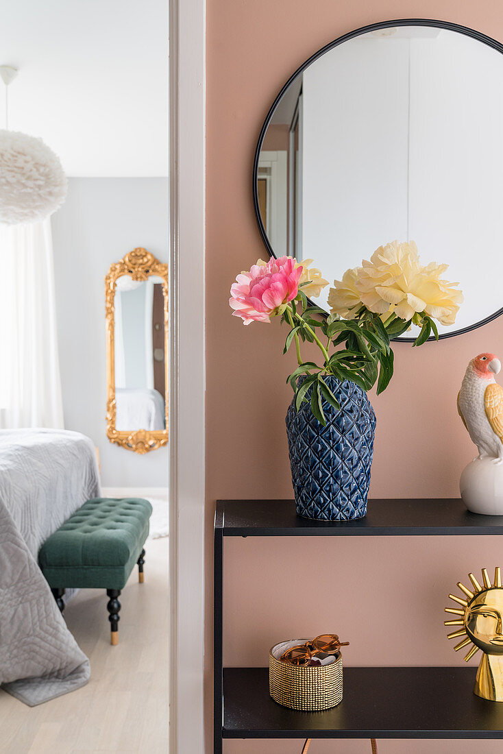 Sideboard und Spiegel an pfirsichfarbener Wand in der Diele, Blick ins Schlafzimmer