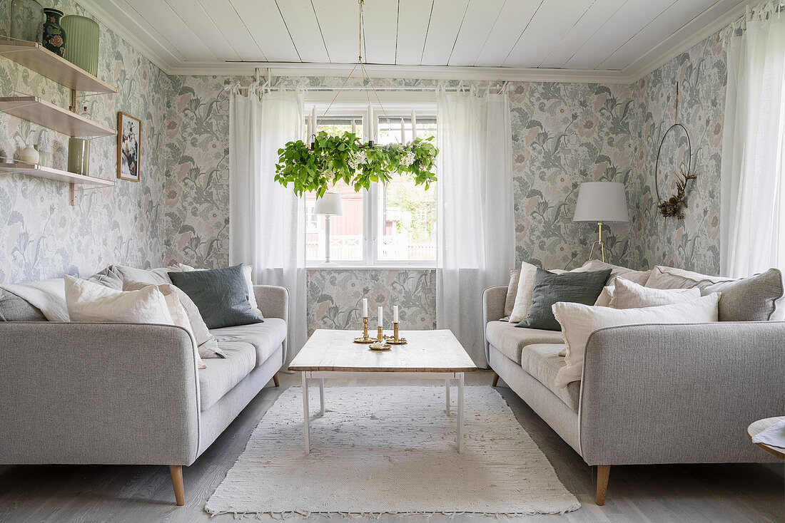 Pale sofas in living room with floral wallpaper