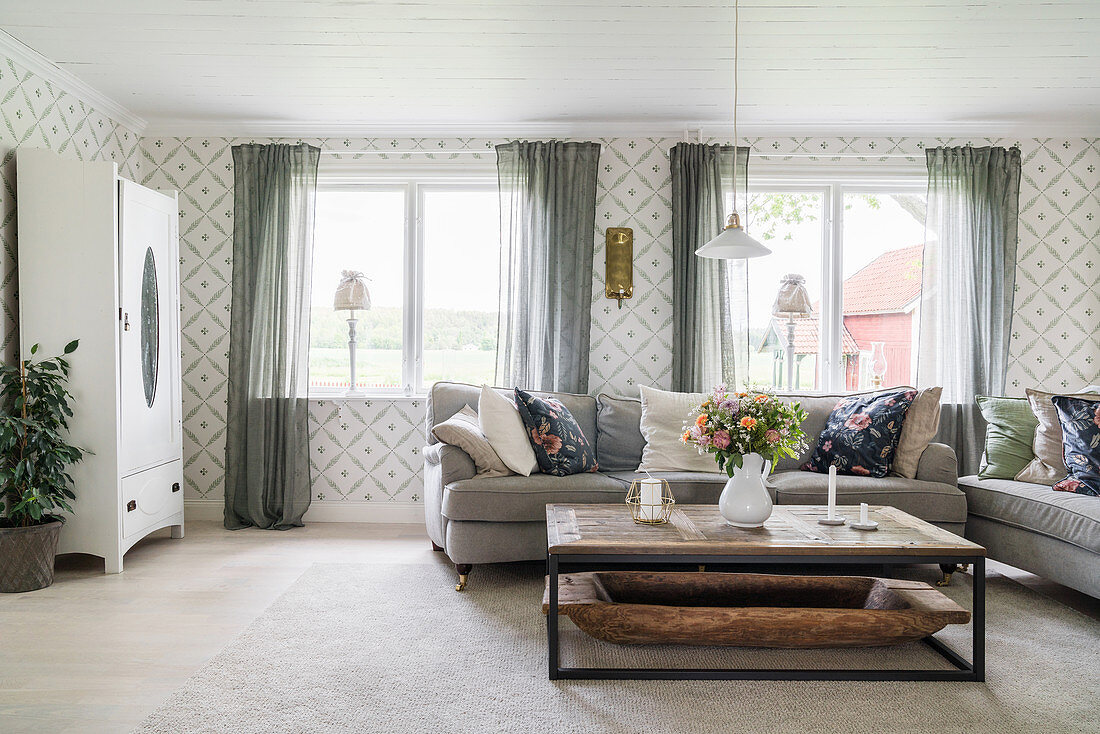 Sofas, coffee table and patterned wallpaper in bright living room