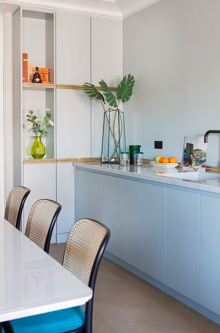 Küchenzeile mit Marmorplatte, im Vordergrund Esstisch mit Bistrostühlen