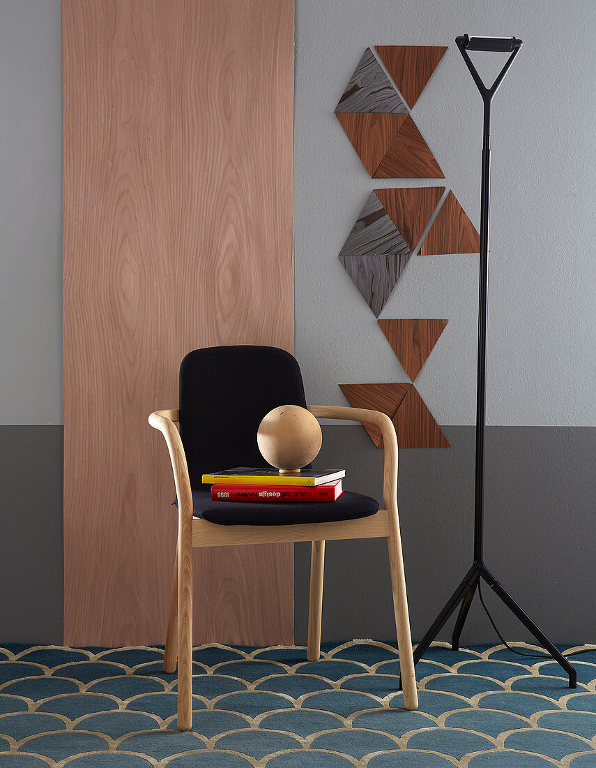 Stuhl vor grauer Wand mit Holzpaneel und Dreiecken aus Furnier