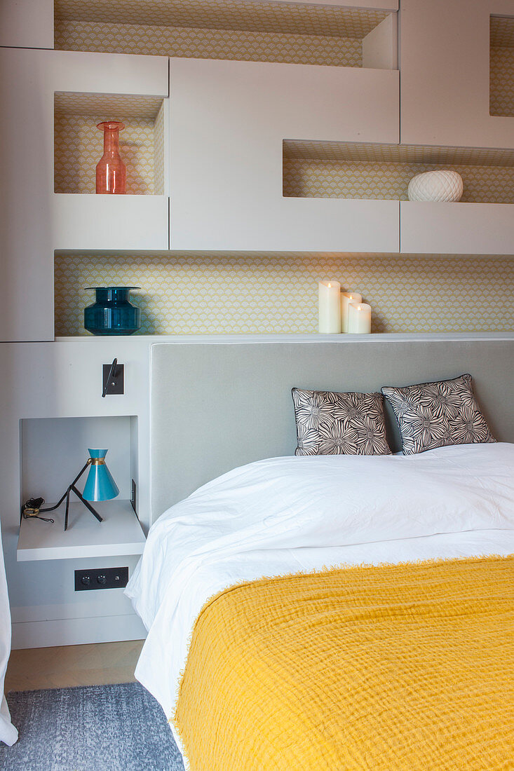 Double bed surrounded by modular shelving in bedroom
