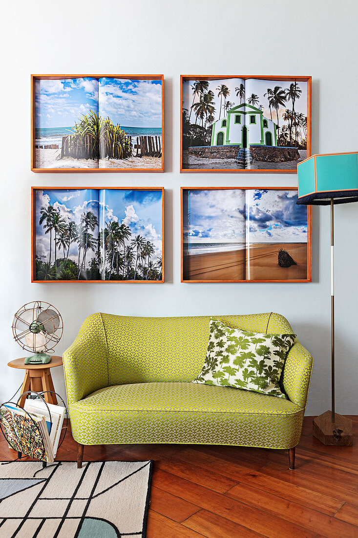 Vier Urlaubsbilder überm kleinen grünen Retro-Sofa im Wohnzimmer