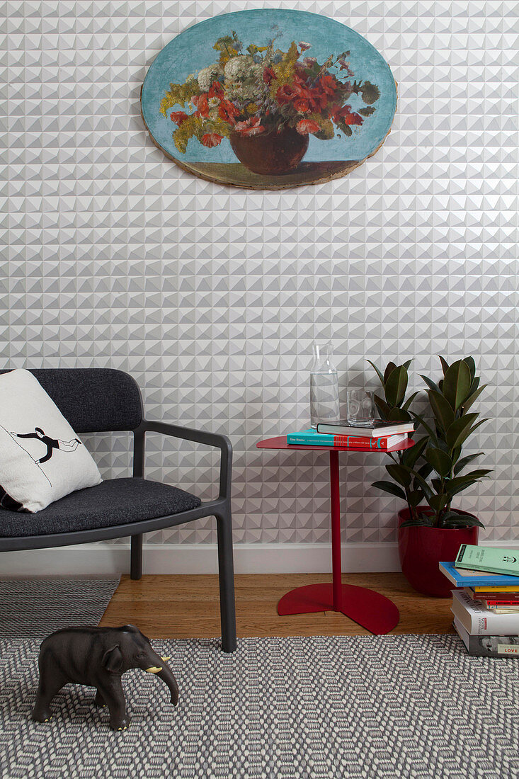 Modern chair and red side table against graphic wallpaper