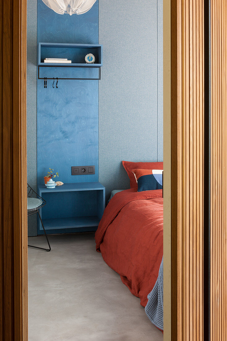 Blue cloakroom panel used as bedside table next to bed