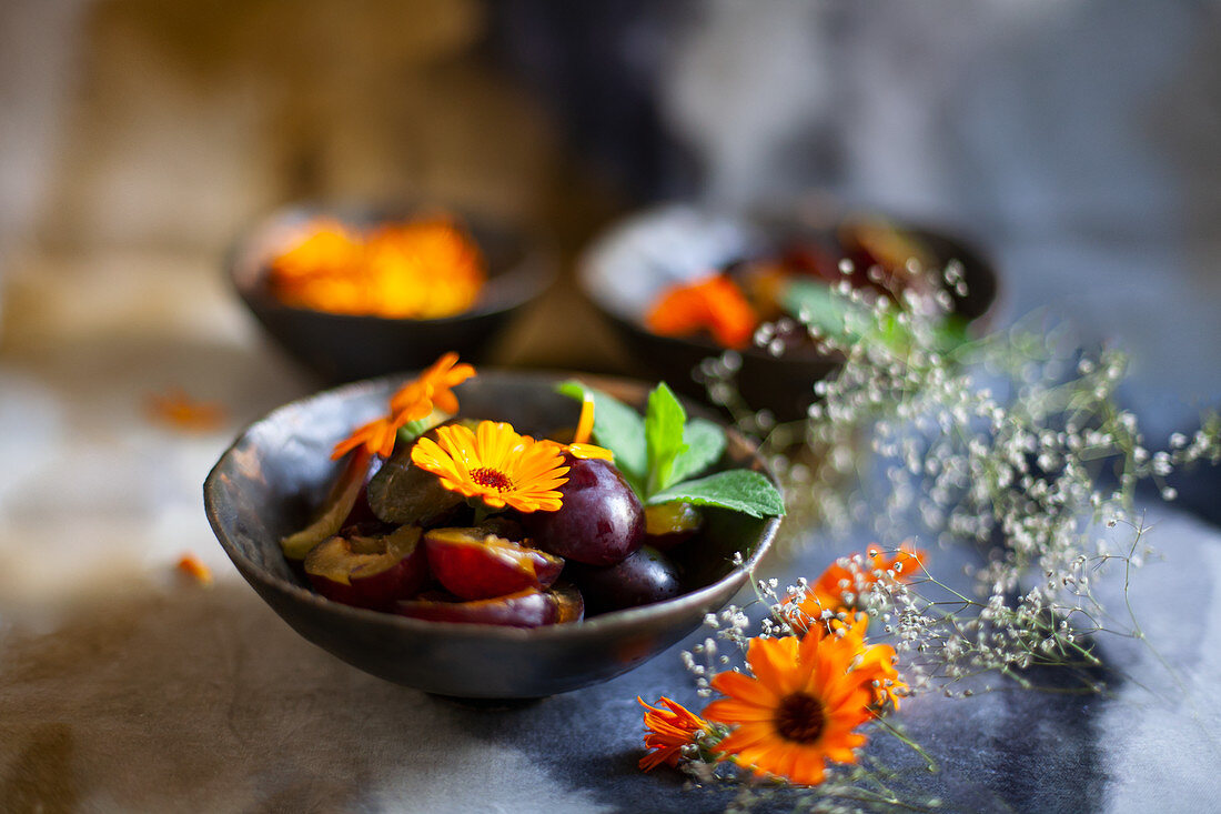 Plums and marigolds in bowl