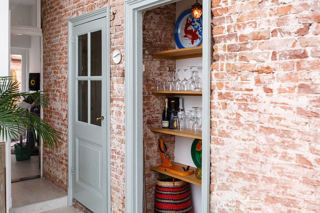 Shelves of crockery in kitchen with brick wall