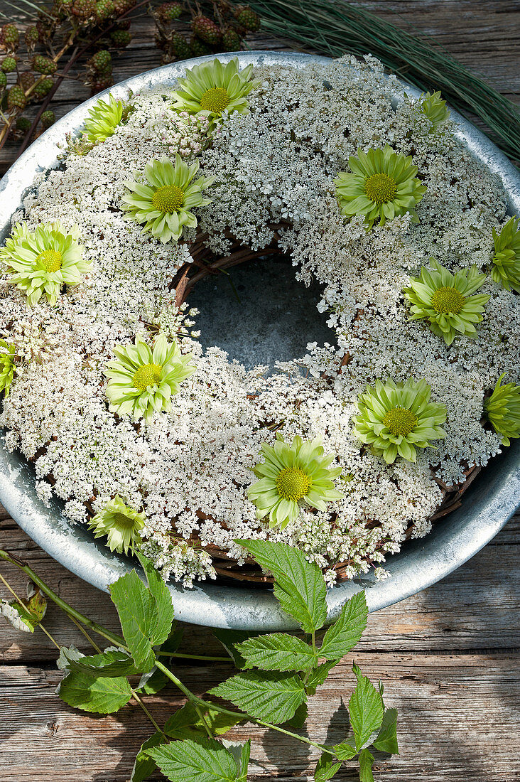 Kranz aus wilder Möhre und grünen Chrysanthemen-Blüten in Zinkschale