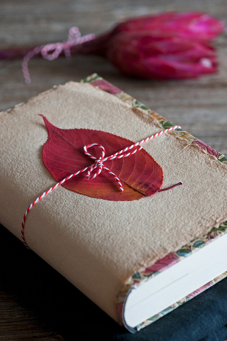 Book gift wrapped with autumn leaf on handmade paper